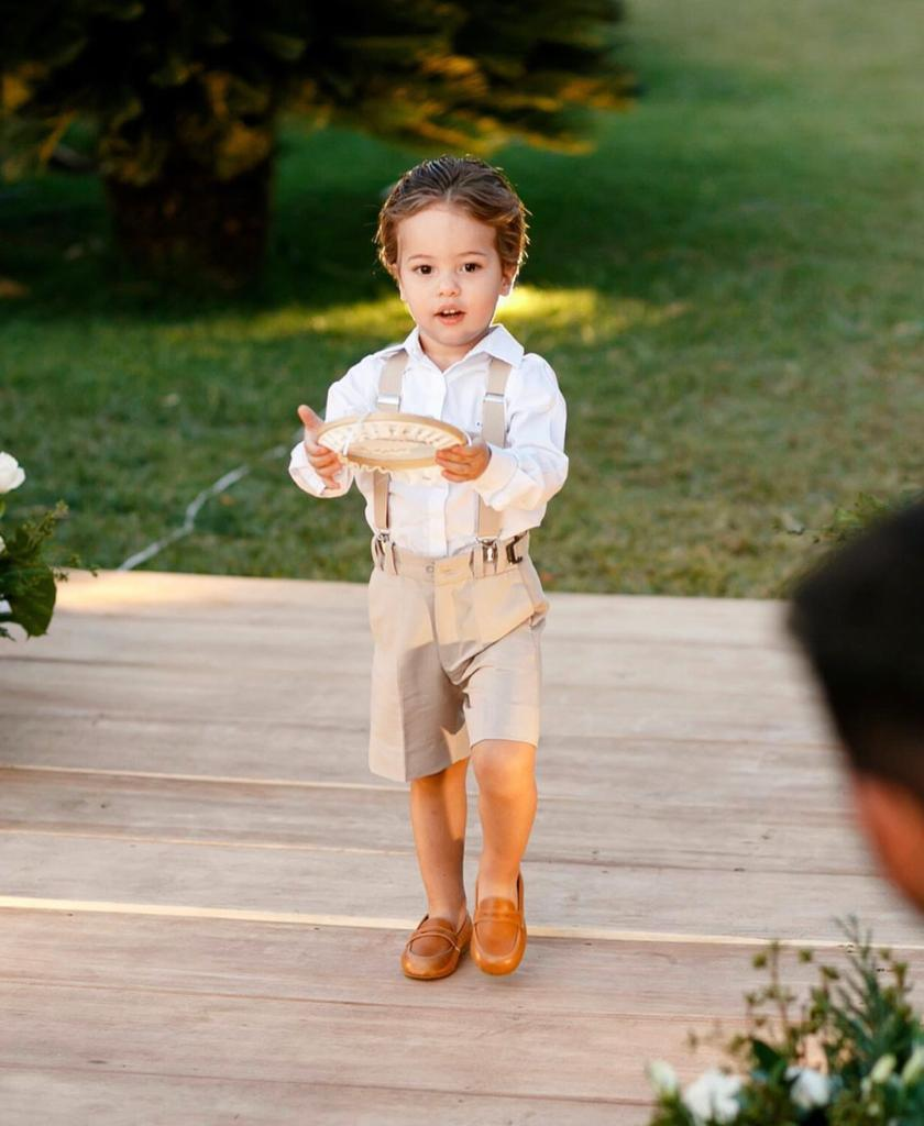 Criança usando conjunto infantil claro com suspensórios e mocassins
